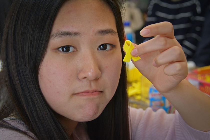 A volunteer makes yellow ribbon pins (the symbol of the Sewol tragedy and the families waiting for their loved ones to return) at Gwanghwamun in Seoul.
