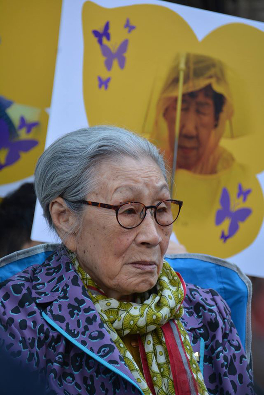 Comfort Women: Former comfort woman Kim Bok Dong at the weekly demonstration in front of the Japanese embassy in Seoul, South Korea.  A poster of a butterfly (sympol of the Comfort Women) with an image of Kang Il Chul who passed away in 2017.