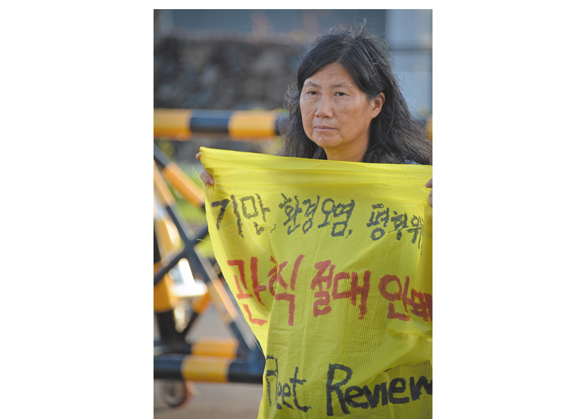 Sunhee Choi holds a sign protesting the planned International Fleet Review, a parade of naval firepower planned for October 2018.  Naval base in Gangjeong, Jeju island, South Korea