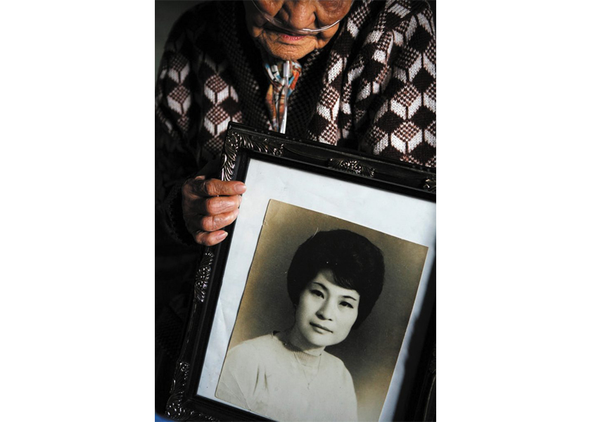 A former camp town prostitute named Bae, holds a photo of herself in her 20s.  Camp Casey in Dongducheon, South Korea.